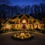 Vertical twilight view of a brick estate and illuminated circular garden
