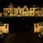 Large-property holiday lighting design with an illuminated roofline, trees and entrance landscaping